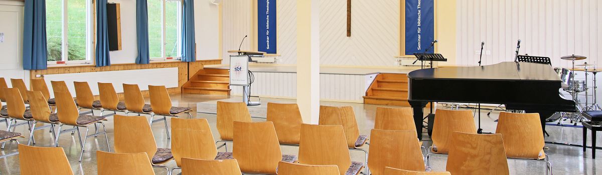 Aula mit Konzert-Bestuhlung, Klavier, Rednerpult, Beamer